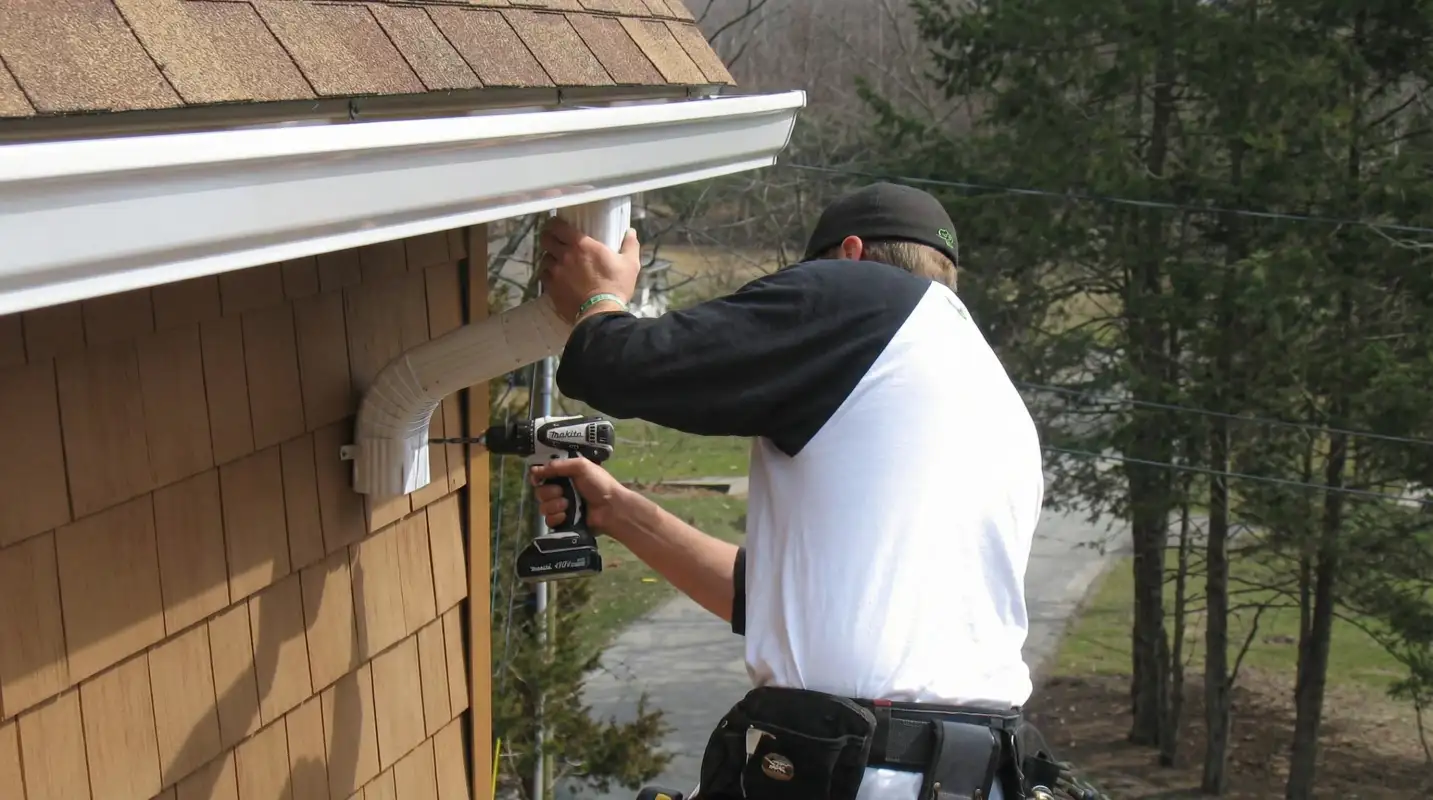 Professional contractor installing tan vinyl siding panels on a residential home exterior in Tulsa, OK